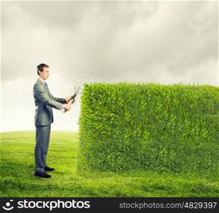 Stop pollution. Young handsome businessman cutting green lawn. Greenery concept