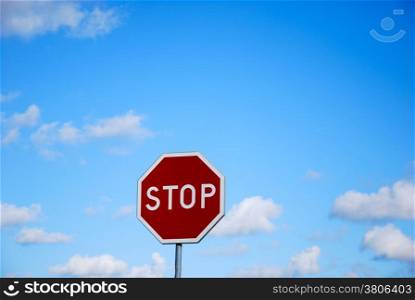 Stop roadsign at blue sky with summer clouds