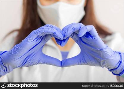 Stop SARS-CoV, SARSCoV, virus 2020 , MERS-CoV ,chinese virus COVID-19. Closeup womens hand in blue medical gloves show heart sign. Concept of protection against HIV. Doctor in blue medical gloves and protective mask. Stop SARS-CoV, SARSCoV, virus 2020 , MERS-CoV ,chinese virus COVID-19. Closeup womens hand in blue medical gloves show heart sign. Concept of protection against HIV. Doctor in blue medical gloves and protective mask.