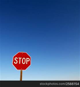 Stop sign in lower left corner with blue sky all around.