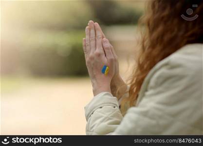 Stop War. Peace in Ukraine. woman hands with picture of flag of ukraine, hands folded in prayer. Antiwar support concept. High quality photo.. Stop War. Peace in Ukraine. woman hands with picture of flag of ukraine, hands folded in prayer. Antiwar support concept. High quality photo