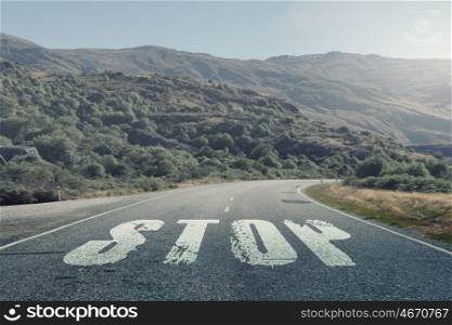 Stop warning on road. Natural landscape and asphalt road with stop word
