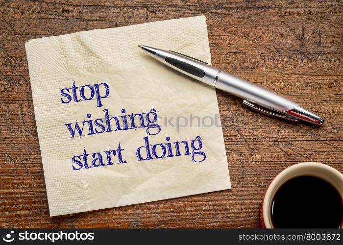 stop wishing, start doing - motivational text on a napkin against grunge wood grunge wood table, top view with coffee
