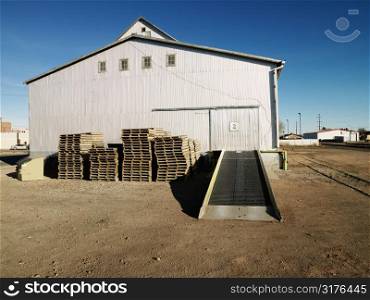 Storage warehouse with ramp and palettes in rural setting.