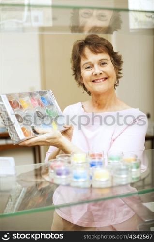 Store clerk or customer in a gift shop, holding up a package of candles.