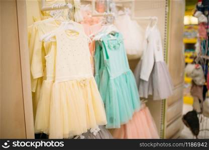 Store for newborns, showcase with dresses in cloth department, nobody. Baby wear in shop of goods for infants