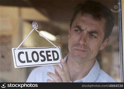 Store Owner Turning Closed Sign In Shop Doorway