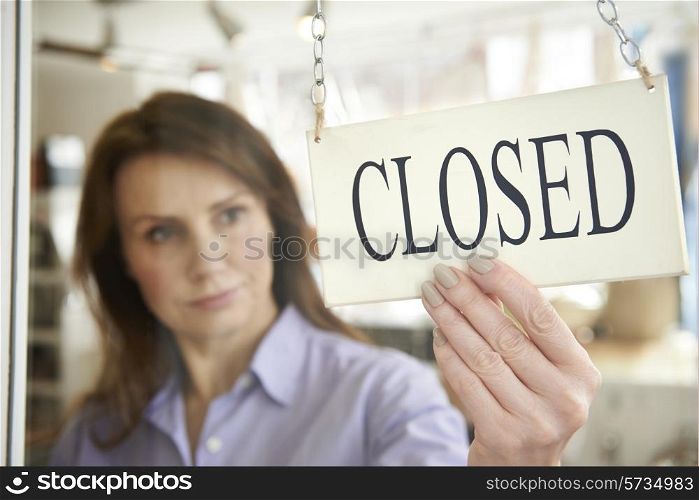 Store Owner Turning Closed Sign In Shop Doorway