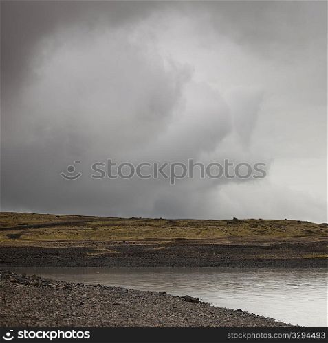 Storm cloud over barren coastline of Jokullsarlon lagoon