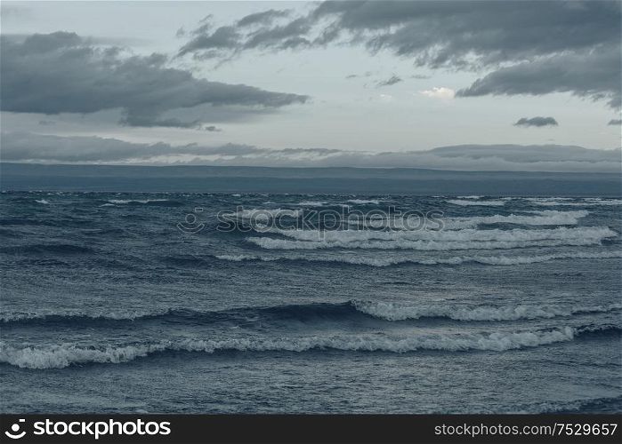 Storm clouds over lake water. Dramatic sky and giant waves.