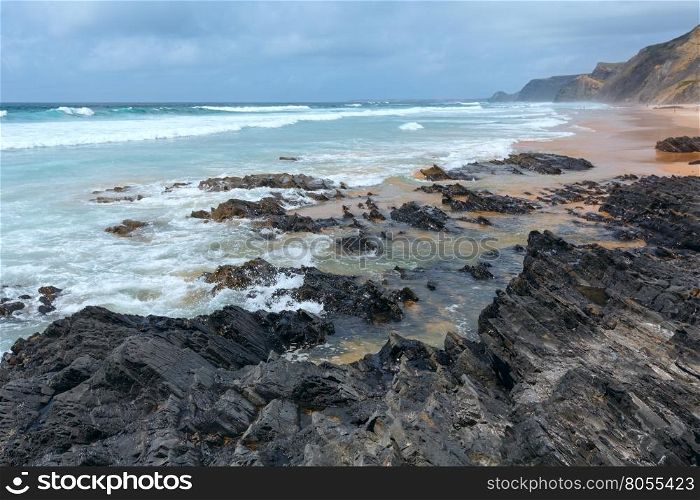 Storm on Castelejo beach with black schist cliffs (Algarve, Portugal). All people are unrecognizable.