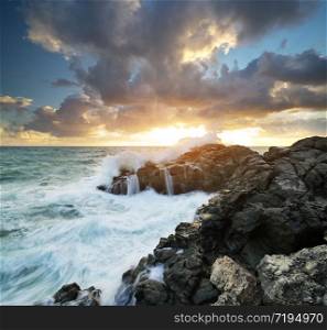 Storm seascape nature composition. Sea waves during storm on sunset splash on stones.