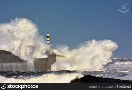 Stormy wave over lighthouse and pier of San Esteban de Pravia in Asturias, Spain.