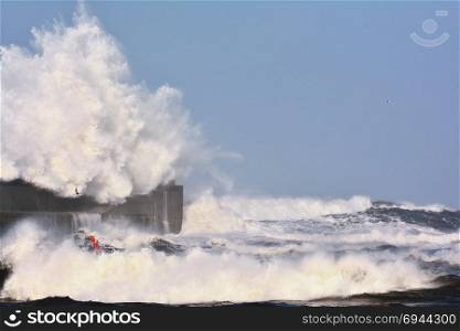 Stormy wave over lighthouse and pier of San Esteban de Pravia in Asturias, Spain.