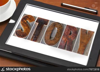 story word in vintage letterpress wood type printing blocks on a digital tablet with a cup of tea