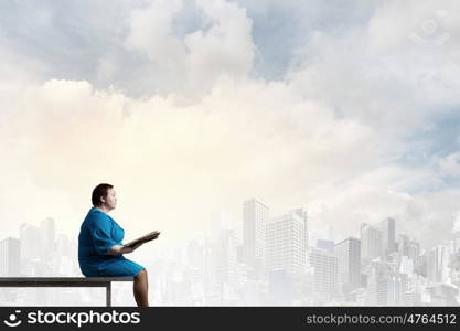 Stout woman. Plus size woman with book in hands sitting on bench