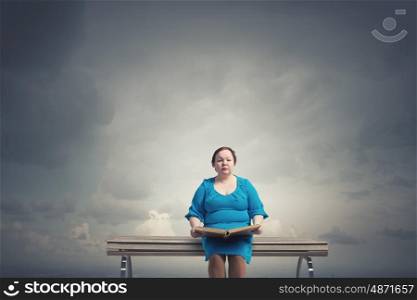 Stout woman. Plus size woman with book in hands sitting on bench