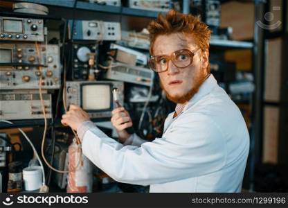 Strange engineer holds electric tube in laboratory. Electrical testing tools on background. Lab equipment, engineering workshop. Strange engineer holds electric tube in laboratory