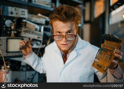 Strange engineer holds electric tube in laboratory. Electrical testing tools on background. Lab equipment, engineering workshop. Strange engineer holds electric tube in laboratory