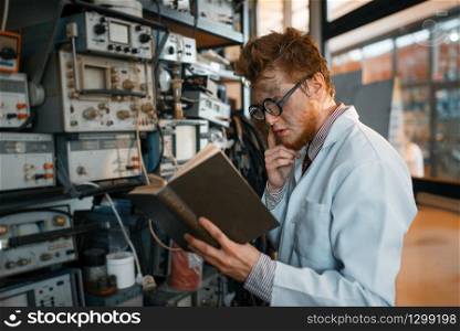Strange engineer with book, test in laboratory. Electrical testing tools on background. Lab equipment, engineering workshop