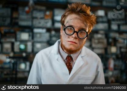 Strange engineer with electric lamps in his ears, test in laboratory. Electrical testing tools on background. Lab equipment, engineering workshop. Engineer with electric lamps in ears, test in lab