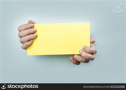 Strange hands holding a yellow card.