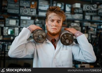 Strange scientist holds radiation devices in his hands, dangerous test in laboratory. Electrical testing tools on background. Lab equipment, engineering workshop. Scientist holds radiation devices in his hands