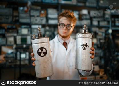 Strange scientist holds radiation materials in his hands, dangerous test in laboratory. Electrical testing tools on background. Lab equipment, engineering workshop