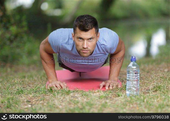 strapping young lad doing pushups in park