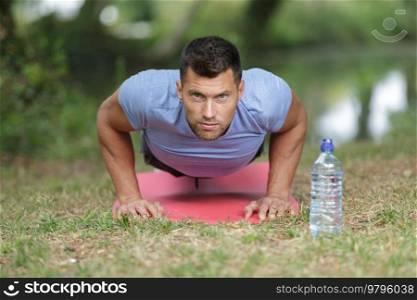 strapping young lad doing pushups in park