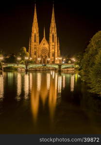 Strasbourg, France night photography with the beautiful St. Paul church with its two majestic towers and their water reflection