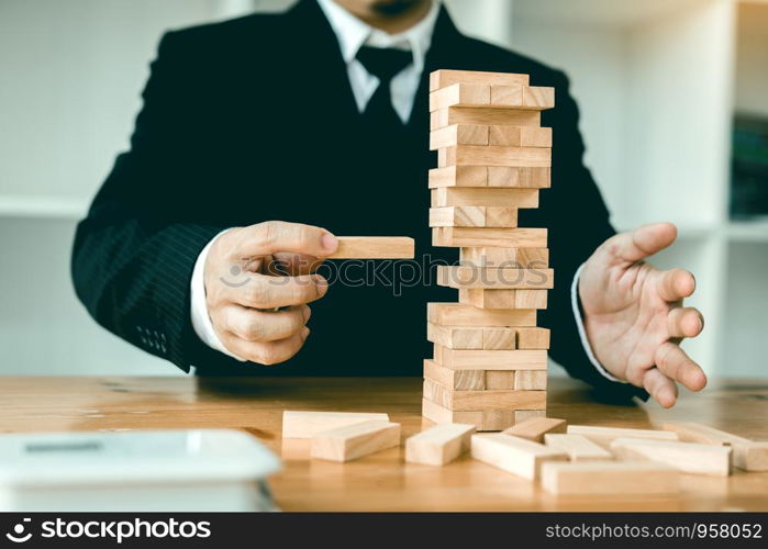Strategic thinking and risk by business people pulls wooden blocks from the group.