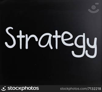 ""Strategy" handwritten with white chalk on a blackboard"