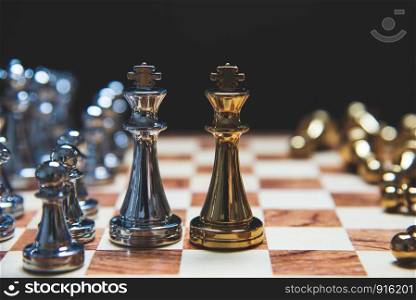 Strategy of leadership as king facing each other in wooden chess board in checkmate position. Business marketing of competition trade partners tactics fighting concept on black background