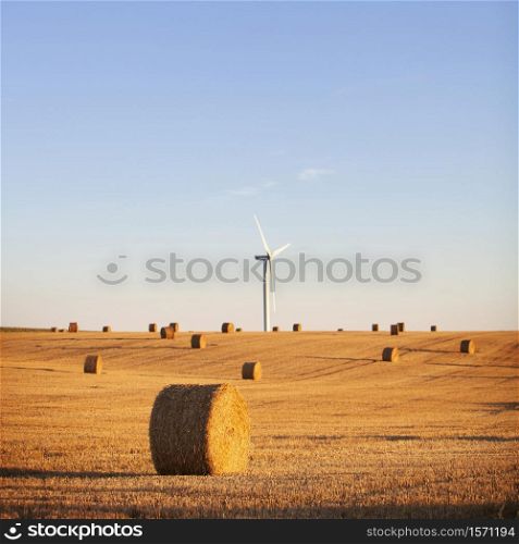 straw bales and wind turbine in late evening light on countryside of french normandy near calais and boulogne