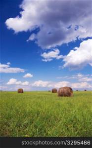 Straw bales on field under blue sky