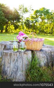 Straw basket with beautiful flowers and summer drinks-mojito. Bright summer picnic