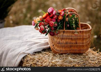 straw basket with flowers on a straw stack covered with a linen tablecloth outdoors on summer suny day.. straw basket with flowers on a straw stack covered with a linen tablecloth outdoors on summer suny day
