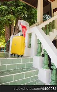 straw hat and a yellow bag on the steps of the house