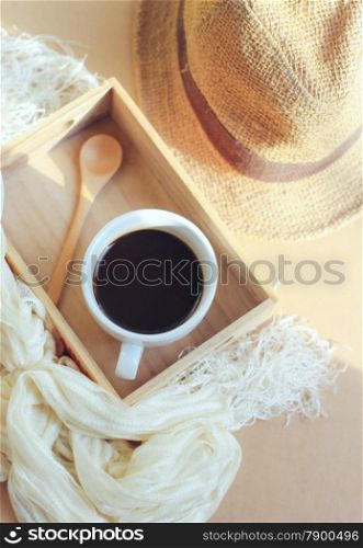 Straw hat with black coffee and spoon on wooden tray, retro filter effect
