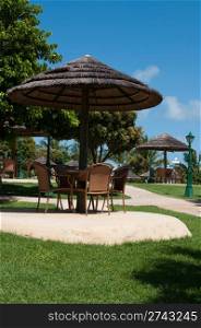straw umbrella and chairs in a tropical resort (next to the swimming pool)