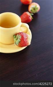 strawberries and a cup with saucer on a wooden table