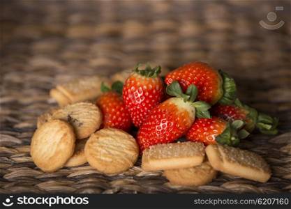 strawberries and biscuits on wooden table in front of a wooden background