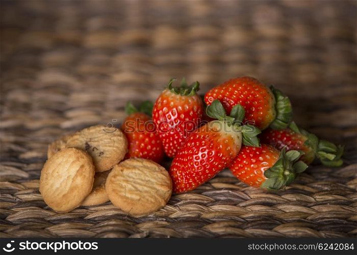 strawberries and biscuits on wooden table in front of a wooden background