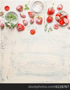 Strawberries and eating ingredients on white rustic background, top view, border