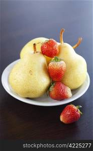 strawberries and pears on a plate on a wooden table