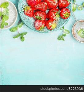 Strawberries border with mint and sugar on turquoise shabby chic background, top view, place for text