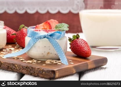 Strawberries desert with cream and cereals served on glass cups over table top.