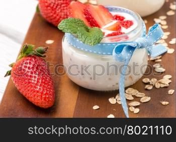 Strawberries desert with cream and cereals served on glass cups over table top.