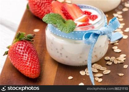 Strawberries desert with cream and cereals served on glass cups over table top.